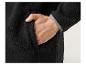 Gros plan sur une veste en polaire noire avec une main dans la poche.