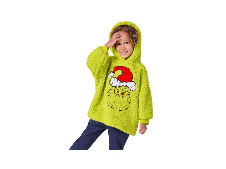 Garçon en sweat à capuche vert Grinch et pantalon bleu foncé.