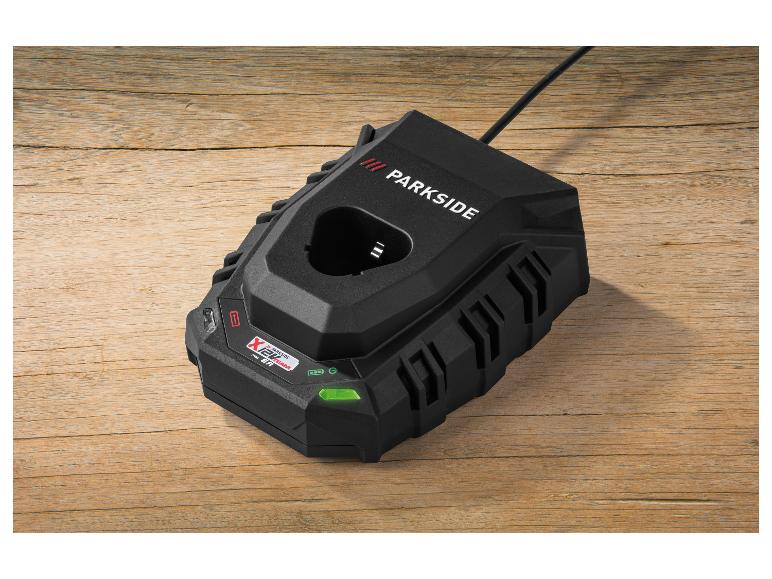 Chargeur de batterie noir sur une table en bois, avec un indicateur LED vert.