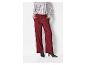 Une femme en chemise rayée et pantalon bordeaux.