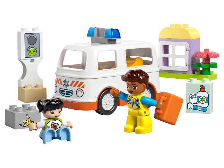 Ambulance jouet, deux figurines et blocs de construction dont une maison et un feu de signalisation.