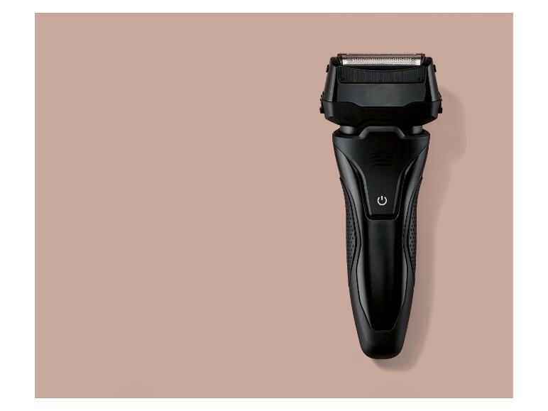 Rasoir électrique noir sur fond rose-beige.