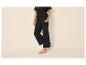 Femme en pantalon noir large et sandales blanches.