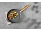 Poêle avec manche en bois, contenant une côtelette, des champignons et des herbes.