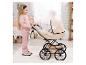 Fille en rose poussant une poussette de poupée beige avec un sac assorti dans une chambre d'enfant.