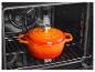 Cocotte émaillée orange dans un four.