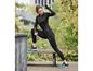Femme vêtue de vêtements de sport noirs et de chaussures de running bleues Skechers.