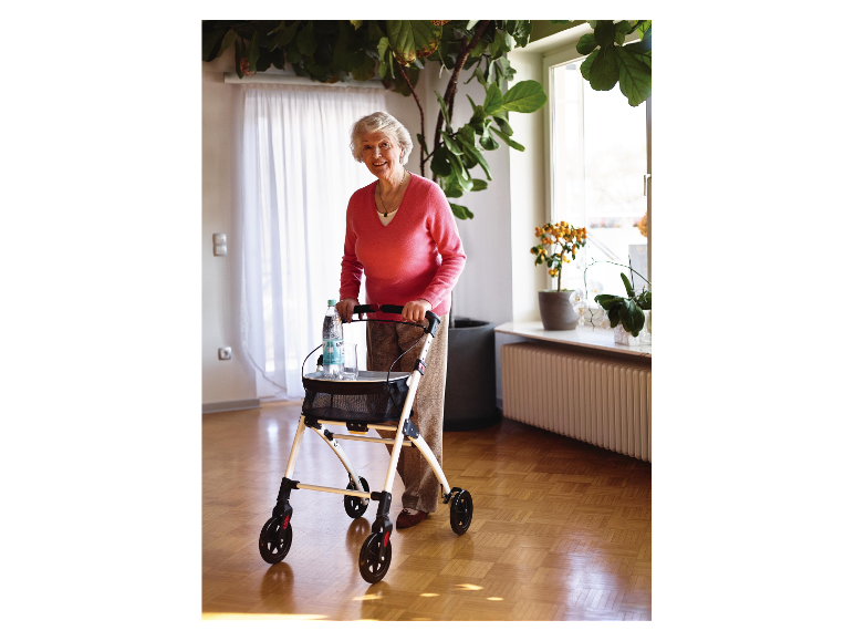 Une dame âgée souriante utilise un déambulateur avec une bouteille d'eau.