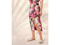 Une femme porte une jupe maxi rose à imprimé floral et des espadrilles.