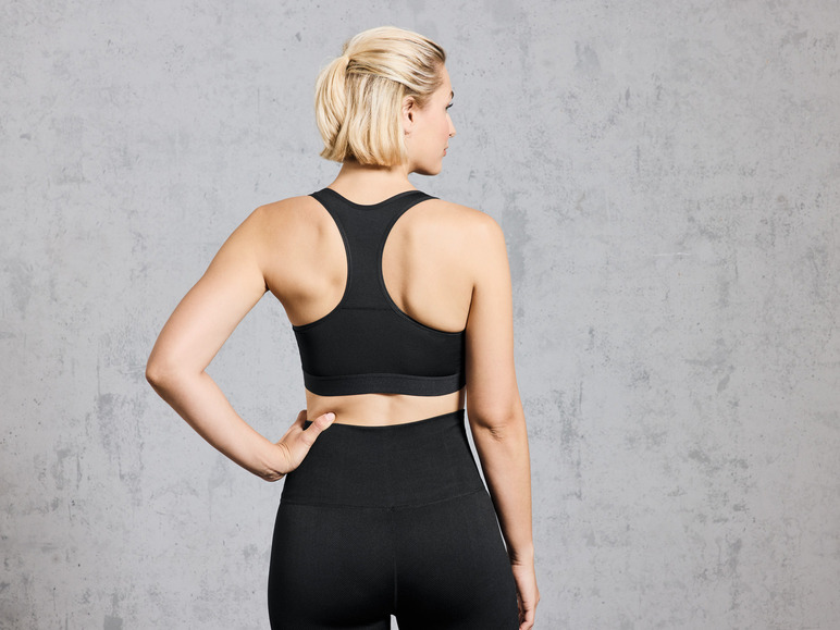 Une femme porte un soutien-gorge de sport et un legging noirs.