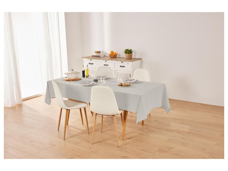 Nappe de table grise, chaises et vaisselle sur une table dans une salle à manger.