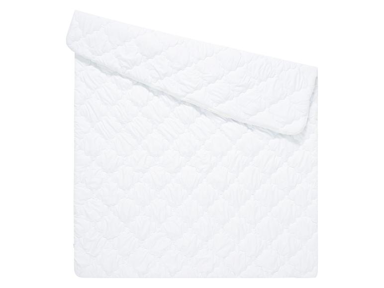 Une couette blanche matelassée pliée sur un fond blanc.