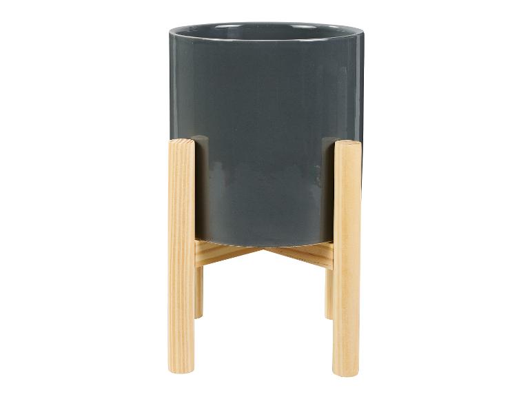 Un pot de fleurs gris sur un support en bois.