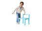 Fille en cardigan et jean bleu, appuyée sur une chaise bleue.