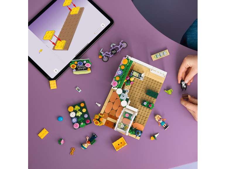 Vue de dessus d'une personne construisant un magasin de fleurs jouet avec une tablette d'instructions.