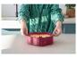 Personne en chemise verte tenant un moule à gâteau en forme de cœur avec de la pâte.