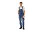 Homme en salopette en jean bleu et t-shirt blanc, main dans la poche.