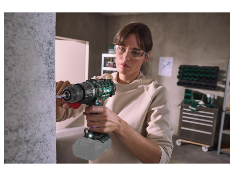 Femme avec des lunettes de protection utilisant une perceuse sans fil PARKSIDE pour percer un mur.