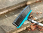 Un balai bleu avec un long manche se trouve sur des marches en béton.