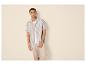 Homme en chemise rayée et pantalon beige.