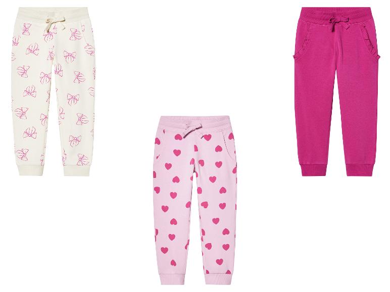 Trois joggings pour filles : un imprimé nœuds, un imprimé cœurs, un rose uni.