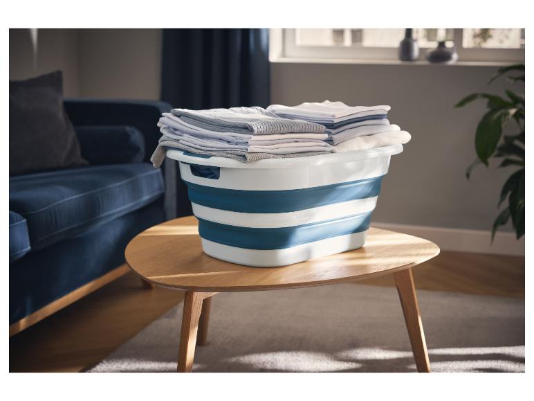 Panier à linge pliable W5 avec des vêtements pliés sur une table en bois dans un salon.