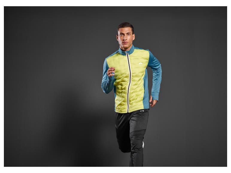 Un homme portant une veste de sport bleue et jaune et un pantalon de jogging noir court.
