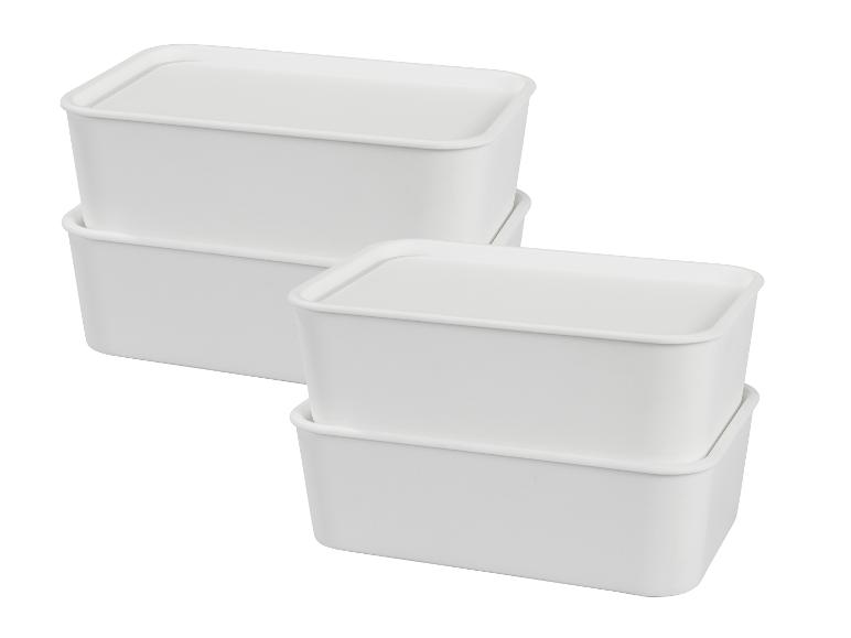 Quatre boîtes de rangement blanches empilées avec couvercles.