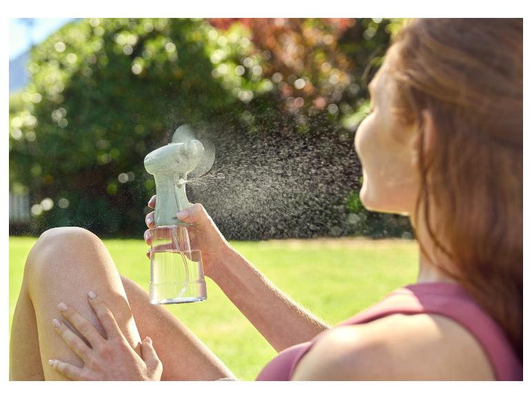 Ventilateur et brumisateur portable rafraîchissant une femme dehors.