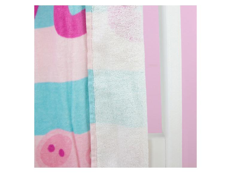 Serviette rose et bleue avec motif de cochon, suspendue près d'un mur blanc.