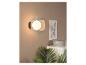 Un luminaire mural moderne avec une ampoule en verre transparent accrochée à un mur beige.