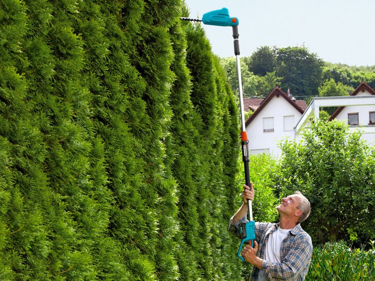 Un homme taille une haie avec une taille-haie Gardena.