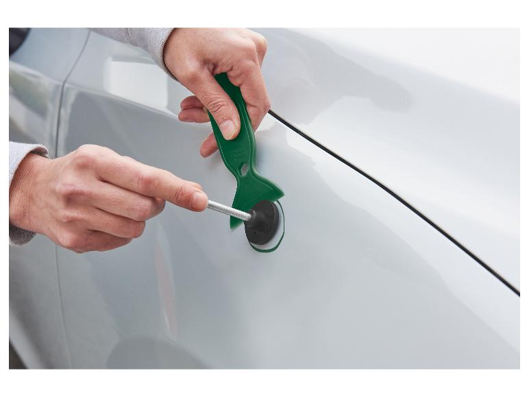 Mains utilisant un kit de réparation de bosses sur une aile de voiture blanche