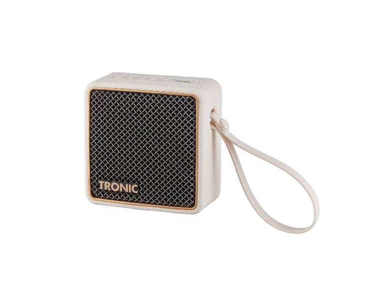 Enceinte portable couleur ivoire avec un cadre doré et une grille de haut-parleur noire.