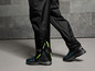 Pantalon imperméable noir avec des bandes réfléchissantes et des chaussures de marche noires.