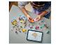 Enfant construisant avec des briques et figurines LEGO Friends colorées, suivant les instructions sur une tablette.