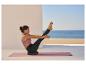 Femme faisant du yoga sur un tapis et un coussin d'équilibre, avec vue sur la mer.