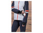 Une femme porte une veste de ski bleue avec des accents rouges et un pantalon assorti.