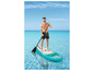 Un homme sur une planche de paddle gonflable dans une eau turquoise.