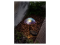 Un luminaire de jardin en forme de champignon, alimenté par énergie solaire, éclaire un parterre.