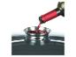 Du vin rouge est versé dans un entonnoir en acier inoxydable posé sur une casserole foncée.