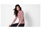 Une femme portant un pull rose et un pantalon noir.