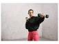 Une femme en sweat-shirt noir et leggings roses s'entraîne avec des haltères.
