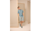 Homme en chemise bleu clair à manches courtes, short gris et baskets.