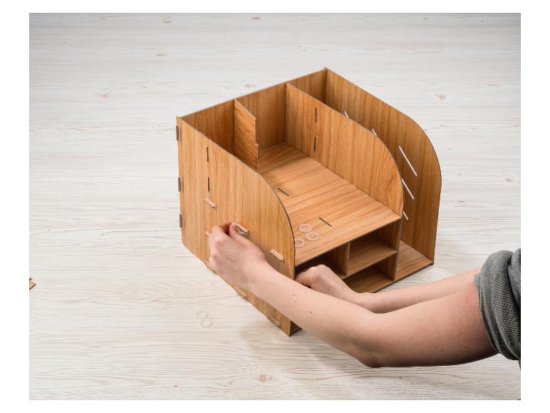 Un organisateur de bureau en bois avec de multiples compartiments, en cours d'assemblage.