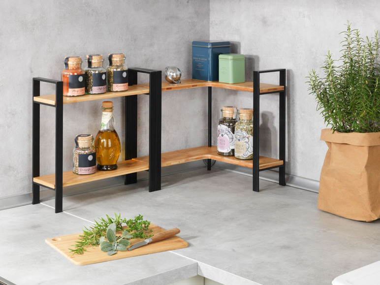 Une étagère d'angle en bois avec des pieds en métal noir, remplie d'herbes, d'épices et d'une bouteille d'huile.