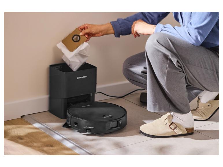 Personne changeant le sac à poussière d'une station de vidage automatique pour robot aspirateur.