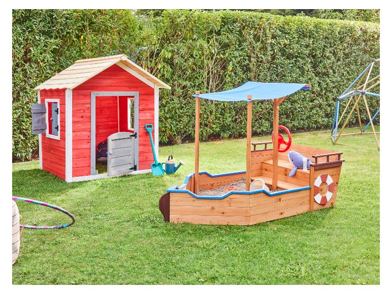 Aire de jeux extérieure pour enfants avec une cabane rouge et un bac à sable en forme de bateau