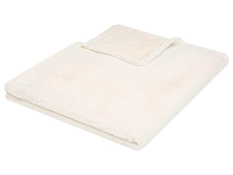 Couverture crème, moelleuse en fausse fourrure, pliée sur fond blanc.