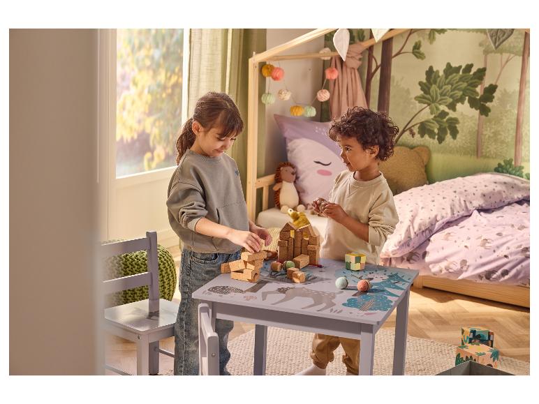 Deux enfants jouent avec des blocs de construction et des jouets à une table d'enfants sur le thème de la forêt.